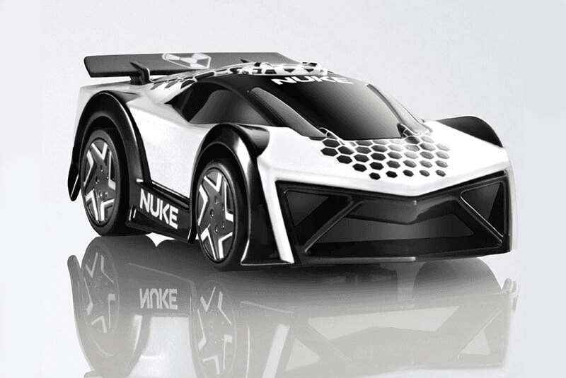 Black and white Nuke toy race car with a rear spoiler, reflected on a glossy surface