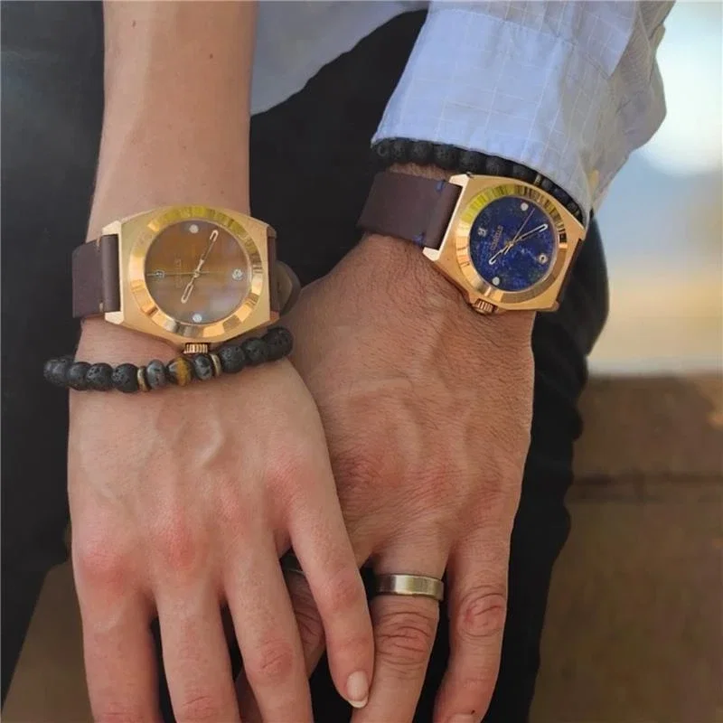 Two gold-tone watches with tiger eye and lapis stone dials and brown leather straps, worn by a couple